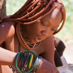 Beautiful Himba woman sewing while singing